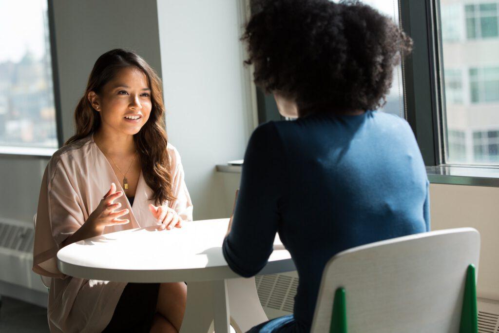 Two women sitting at a table, giving each other feedback.