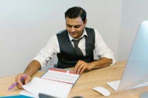 Man working through several schedules laid on the table.