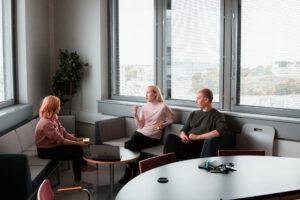 Three people sitting in a meeting room talking.